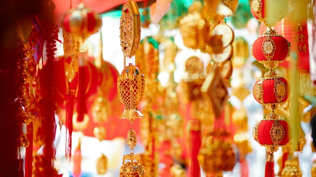 Colorful and ornate Chinese New Year decorations hanging in a festive setting, featuring gold and red elements.