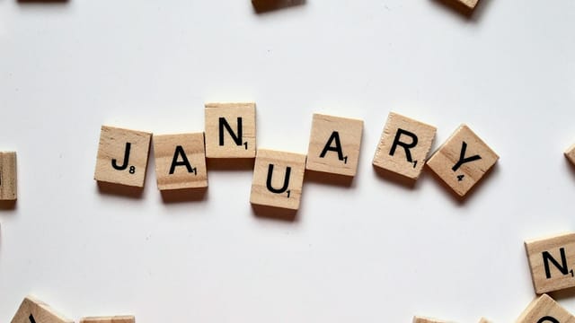 Close-up of Scrabble tiles spelling 'January' on a white surface, perfect for winter or new year themes.
