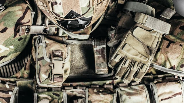 Close-up of tactical military gear with camouflage helmet and gloves showcasing readiness.