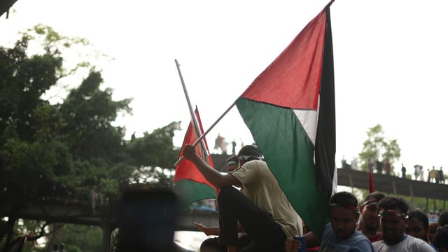 Pro-Palestine rally in Dhaka, Bangladesh with demonstrators waving flags in solidarity.