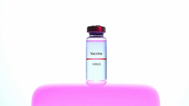 A vaccine vial against a vibrant pink and white background, symbolizing healthcare and medicine.