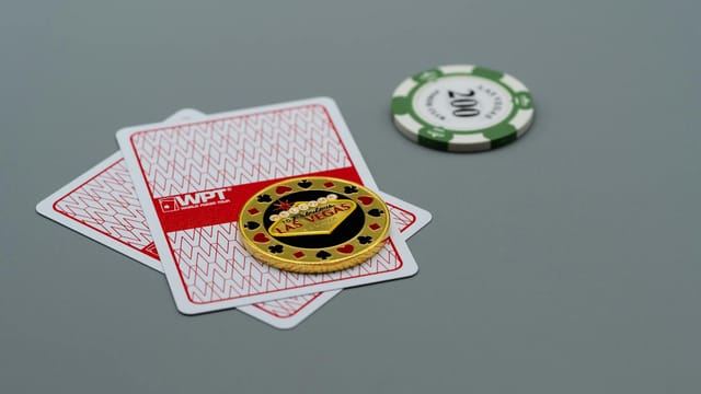 Two playing cards and poker chips, including a Las Vegas chip, on a grey background. Ideal for casino or gambling themes.