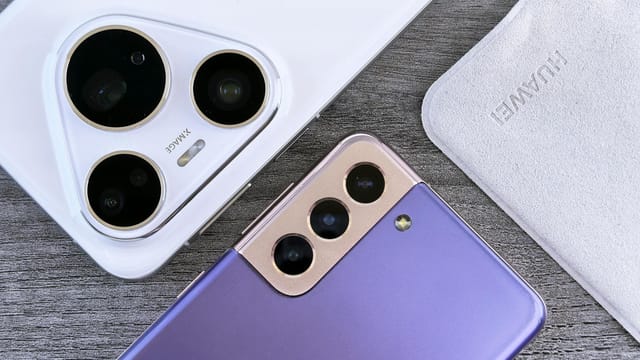 Close-up of two smartphones with camera focus on a textured wooden surface.