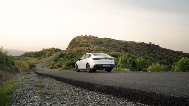 A white car cruises through the scenic landscapes of Shaqlawa, Iraq during a serene sunset drive.