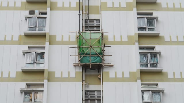 An urban apartment building in Hong Kong featuring traditional bamboo scaffolding for construction.