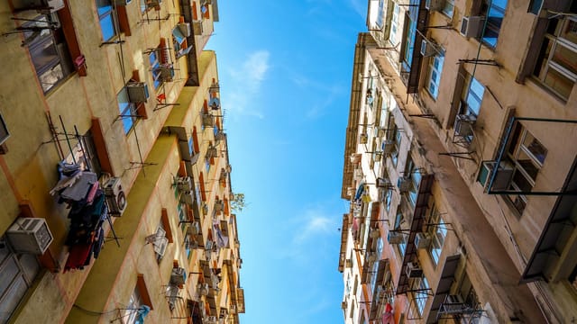 Low-angle view of colorful residential buildings against a vivid blue sky in Hong Kong.