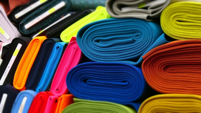 Colorful fabrics neatly rolled and displayed in a textile store.