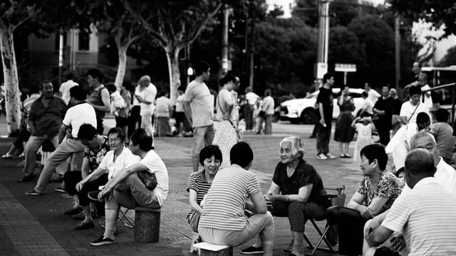 Black and white image of people socializing in a lively Shanghai town square.