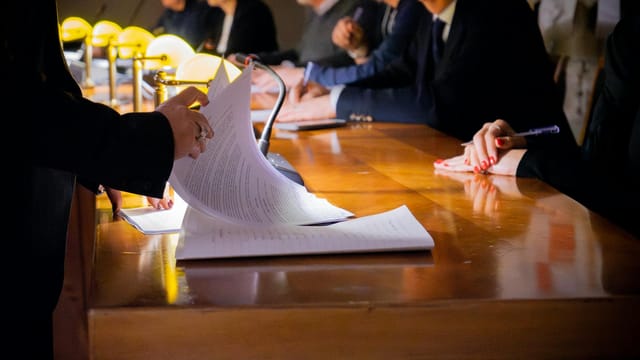Close-up of a business meeting table with documents being reviewed and signed in Bergamo, Italy.