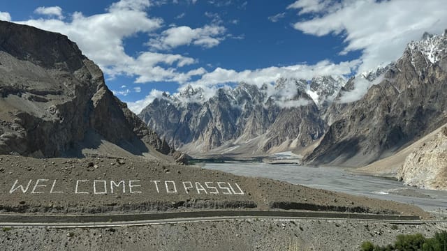 Breathtaking view of the Passu Cones with a welcoming sign, showcasing stunning mountainous landscape in Pakistan.