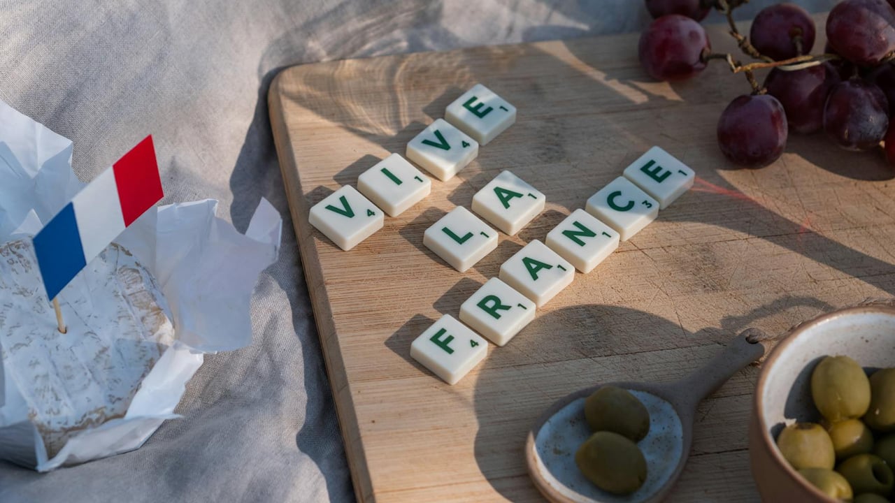 French-themed picnic setup with cheese, grapes, and 'Vive la France' spelled out in letter tiles.