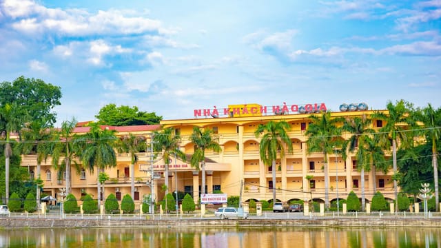 Charming hotel building with palm trees and pond reflection, ideal for travelers in Vietnam.