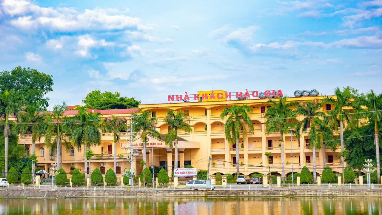 Charming hotel building with palm trees and pond reflection, ideal for travelers in Vietnam.