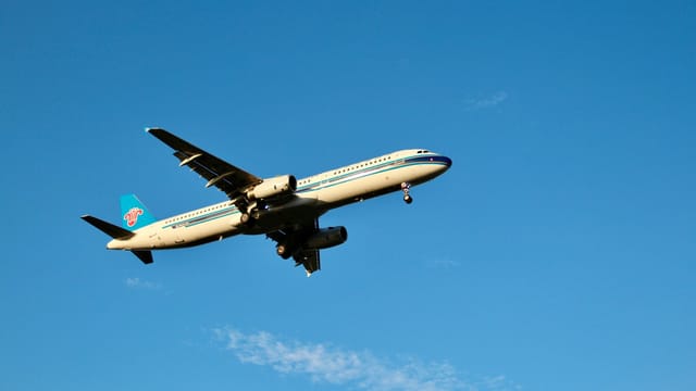 A commercial airplane in flight set against a clear blue daytime sky.