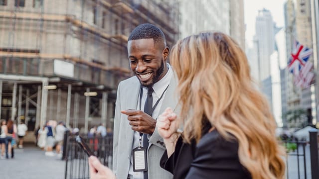 Two business professionals engage in lively conversation on an urban street, sharing insights.