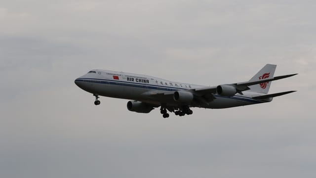 Air China Boeing 747 flying in cloudy skies over Frankfurt, showcasing international travel.
