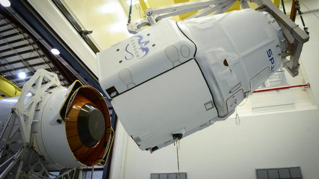 Close-up of a spacecraft being assembled and installed in an industrial facility.