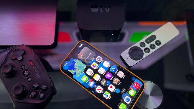 Stylish home entertainment setup featuring an iPhone, Apple TV, and gaming controller on a dark surface.