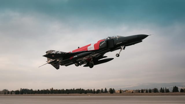 Turkish air force jet soaring over a runway with vivid markings in Türkiye.