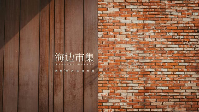 Seaside Market sign on brown wooden panel beside brick wall in Qinhuangdao, China.