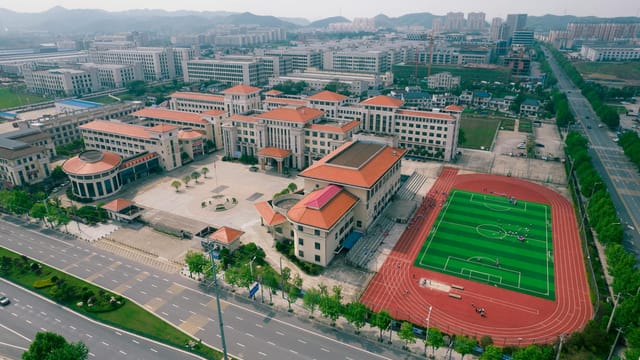 Aerial view of a modern school campus with sports field in Jiujiang, China.