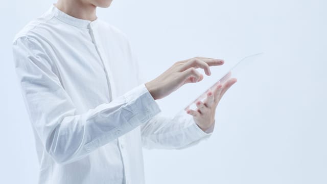 Person interacting with a transparent digital tablet, symbolizing technology and futurism.
