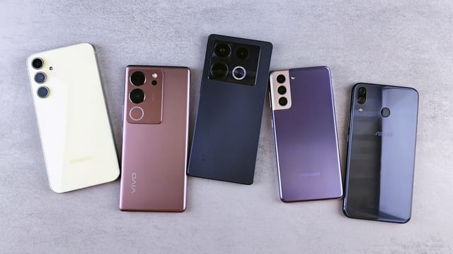 Flat lay of five modern smartphones on a gray surface, showcasing various designs.