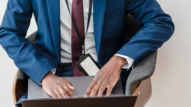 Top view of a businessman in a blue suit using a laptop in a modern office.