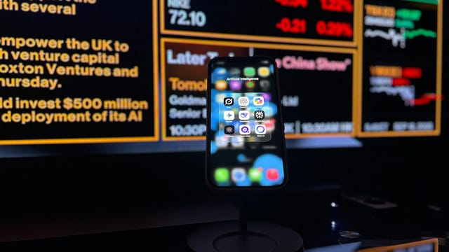 Smartphone displaying AI apps in front of a financial data screen in London.