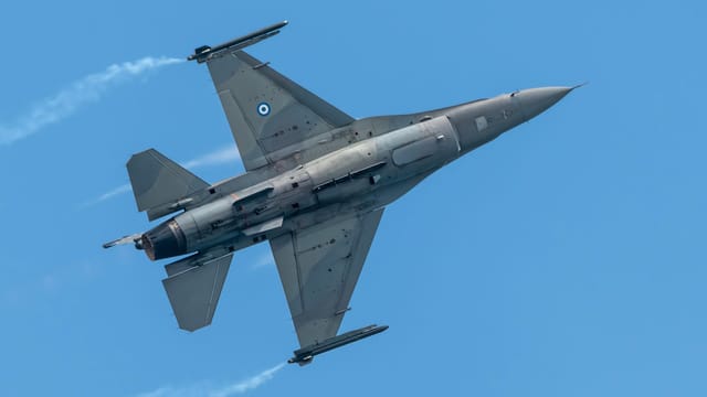 Dynamic shot of a Greek F-16 jet soaring through a clear blue sky, showcasing its sleek design.