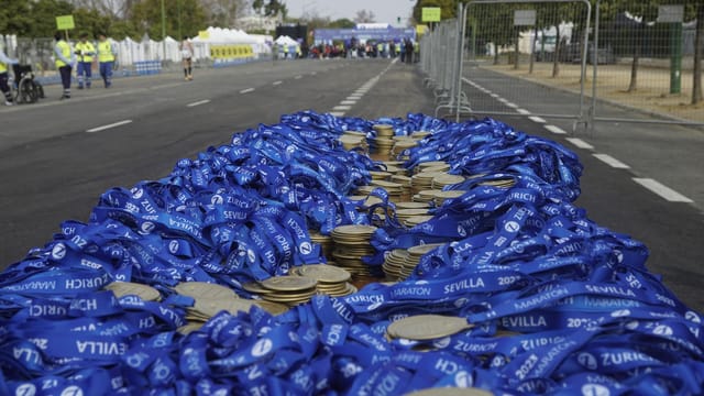 Stack of medals with blue ribbons at Sevilla Marathon, ready for winners' arrival.