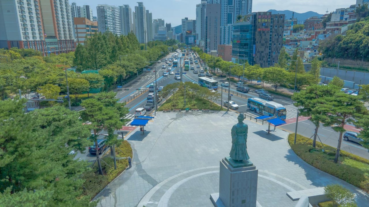 Bustling aerial view of downtown Busan showcasing cityscape and statue.