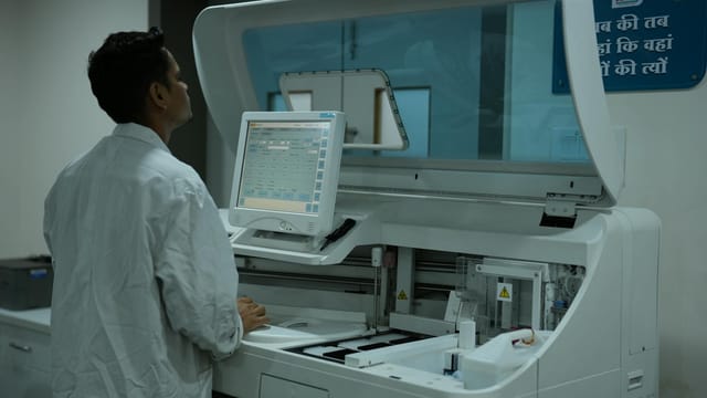 A lab technician operates a clinical analyzer in a modern laboratory setting.