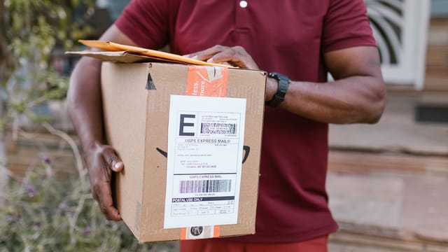 Close-up of a courier delivering a parcel with USPS express mail label outdoors.