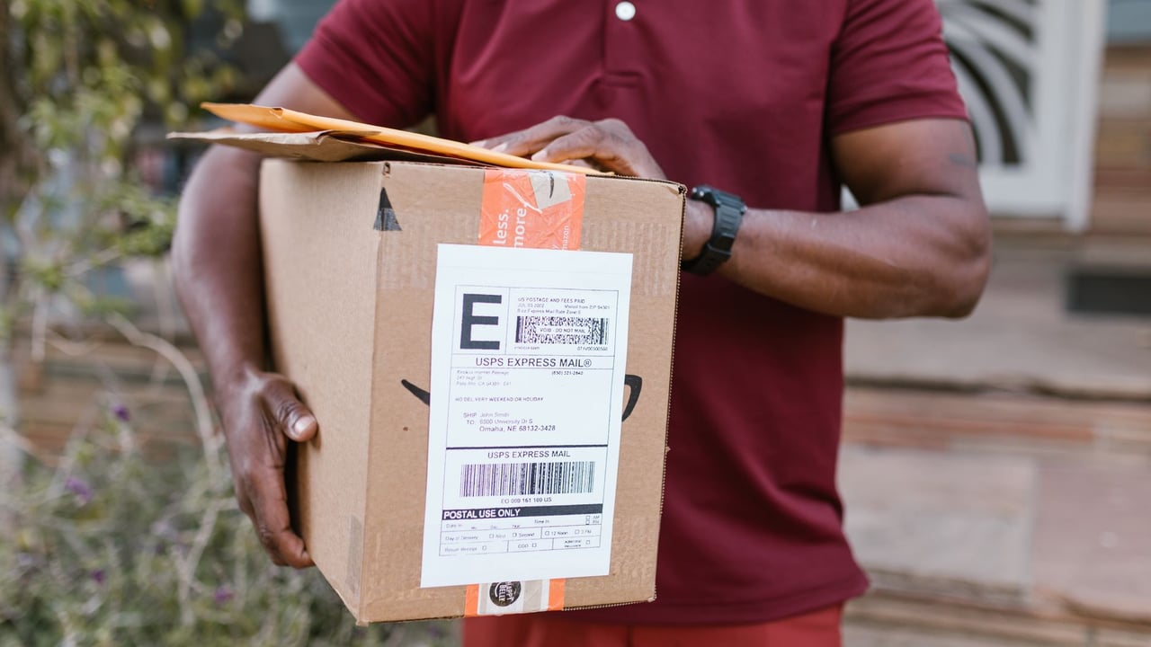 Close-up of a courier delivering a parcel with USPS express mail label outdoors.
