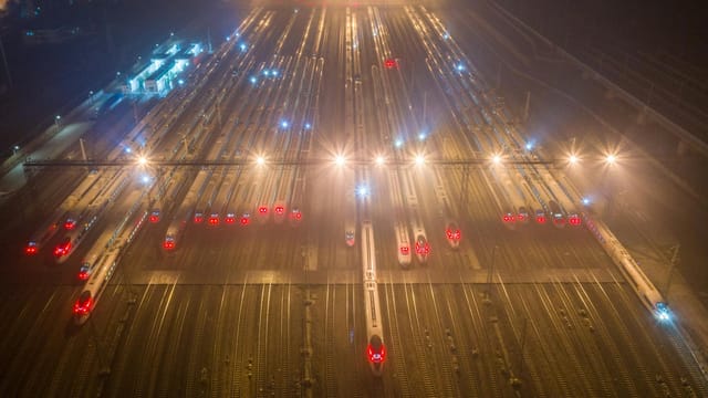 A nighttime aerial view of trains at an illuminated railway station in Nanjing, China.