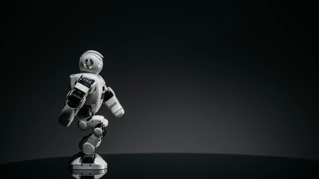 A sleek white toy robot poised elegantly against a dark studio backdrop.