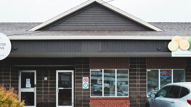 Exterior of contemporary store with glass doors and brick wall with car parked near window