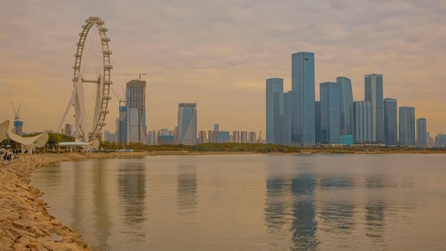Captivating view of Shenzhen skyline and Ferris wheel reflected in the water during twilight.