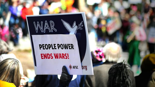Protest sign reading 'People Power Ends Wars!' at a rally in Baltimore.