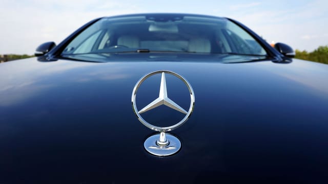 Close-up of a Mercedes-Benz emblem on a luxury car hood featuring a sleek design.