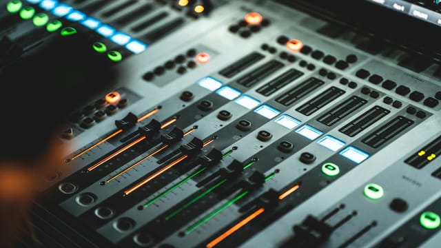 Close-up of a professional audio mixing console with illuminated LED indicators in a music studio.