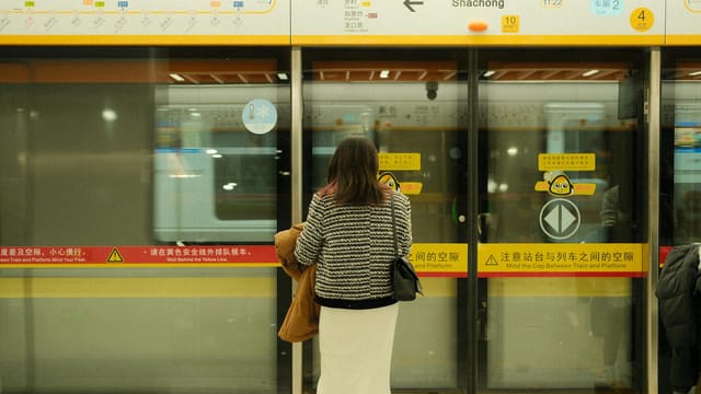 A woman stands on the Shachong metro station platform, waiting for the next train.