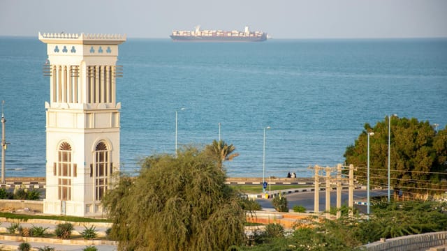 Scenic view of Qeshm Island's coastline featuring a traditional wind tower and the ocean horizon.