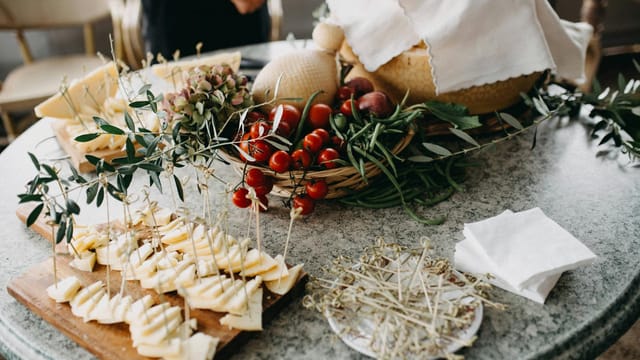 Serving of sliced cheese and cherry tomatoes on a marble table with fresh herbs.