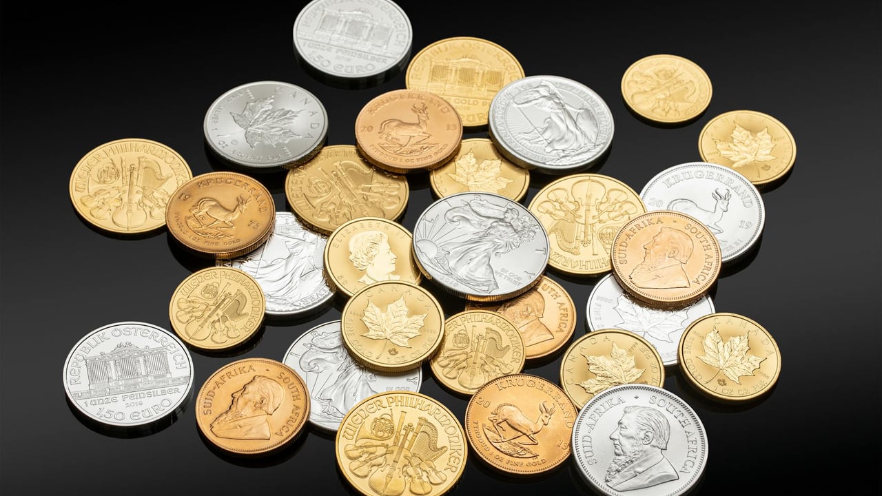 Close-up of assorted coins in silver, gold, and copper on a black background, showing various currencies and denominations.