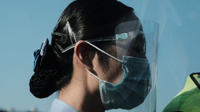 Side view of a woman wearing a face shield and mask, capturing pandemic safety measures.