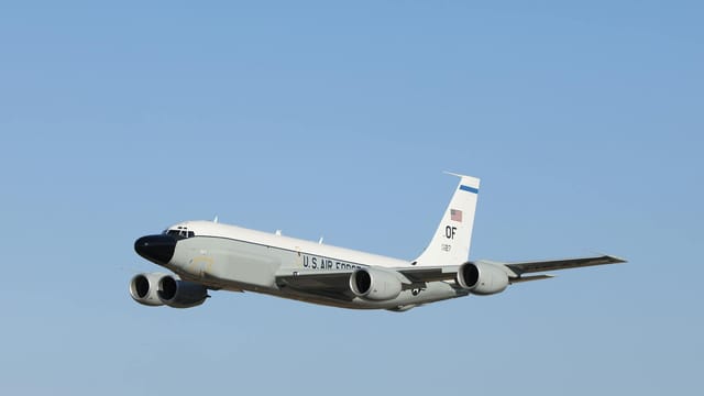 A U.S. Air Force jet flies high in a clear blue sky, showcasing powerful military aviation.