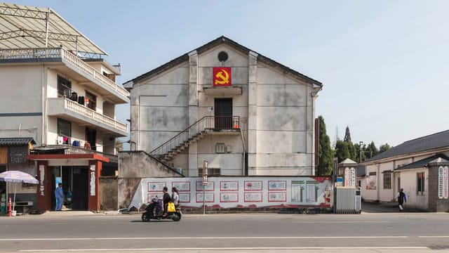 Exteriors of low level buildings decorated with hammer and sickle flag located in suburban area in Communist country