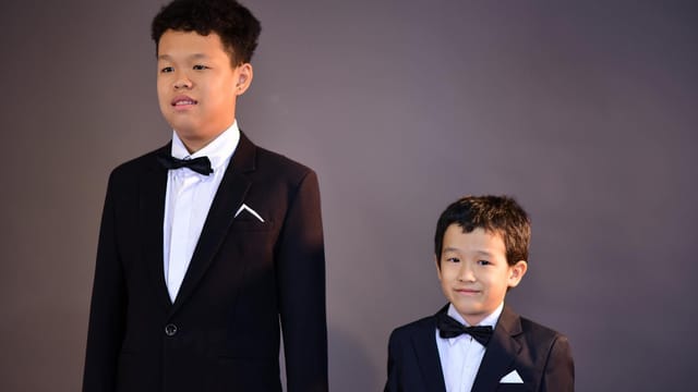 Two boys in elegant suits and bow ties posing for a formal portrait.